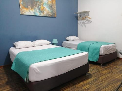 2 Betten in einem Zimmer mit blauen Wänden in der Unterkunft Kayva in Trujillo