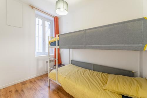 een slaapkamer met een stapelbed met gele lakens en een raam bij La Plume in Marseille