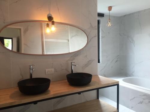 baño con lavabo negro y espejo en HYTTA, en Arendonk