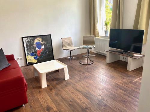 a living room with a red couch and a flat screen tv at Chez Coco Apartment 2 Aachen in Aachen