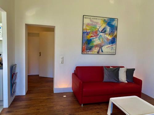 a living room with a red couch and a painting at Chez Coco Apartment 2 Aachen in Aachen