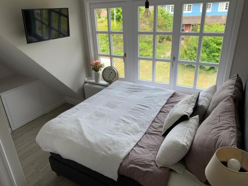 a bedroom with a large bed in front of a window at Keitum - hochwertig und gemütlich Wohnen unter Reet in Keitum