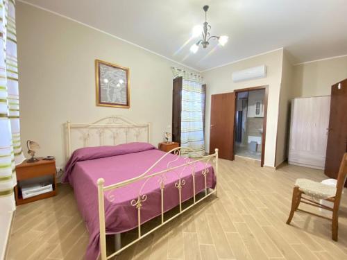 ein Schlafzimmer mit einem rosa Bett und einem Stuhl in der Unterkunft B&B Gloria in Villabate