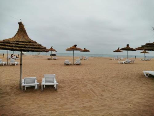 um grupo de cadeiras e guarda-sóis numa praia em Blanca Beach vue latérale sur mer, avec wifi em Sidi Rahal
