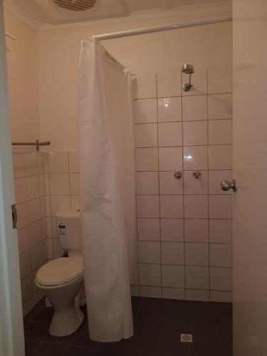 a bathroom with a toilet and a shower with a shower curtain at AGVA OPAL in Coober Pedy