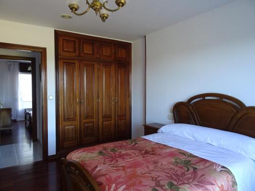 a bedroom with a bed and a wooden closet at La Casa de Vicenta in Arzúa