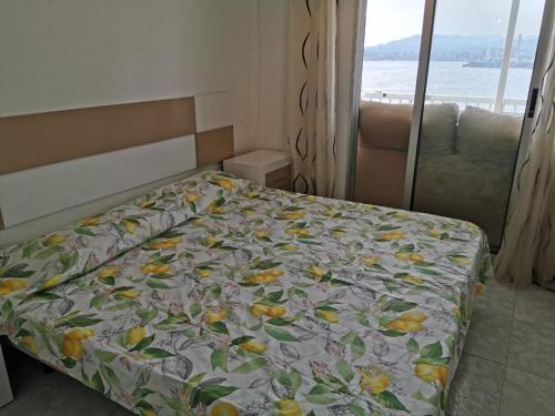 1 dormitorio con 1 cama con colcha de flores y ventana en Apartment Levante, en Benidorm