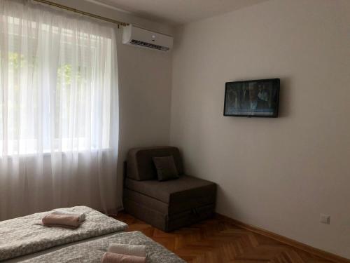 a bedroom with two beds and a chair and a window at Apartment Bregovi in Trebinje