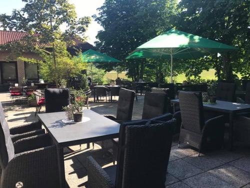 eine Terrasse mit Tischen und Stühlen und einem grünen Sonnenschirm in der Unterkunft Hotel Restaurant Borchard in Lübbecke