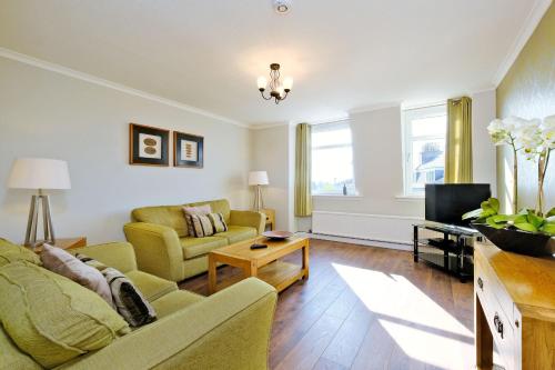 a living room with a couch and a tv at Home from Home Aberdeen-Spacious West End Apartment-Free Parking-Near ARI & City Centre in Aberdeen