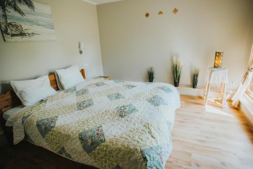 a bedroom with a bed with a quilt on it at Guest House Baltās Dūjas in Saulkrasti
