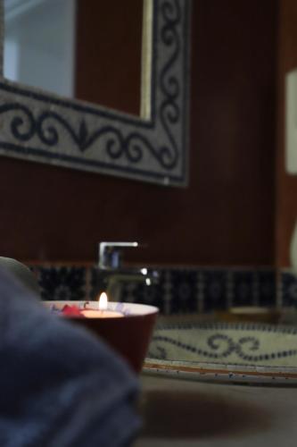 a candle in a bowl in front of a bathroom sink at Dar El Jerbi in Mezraya