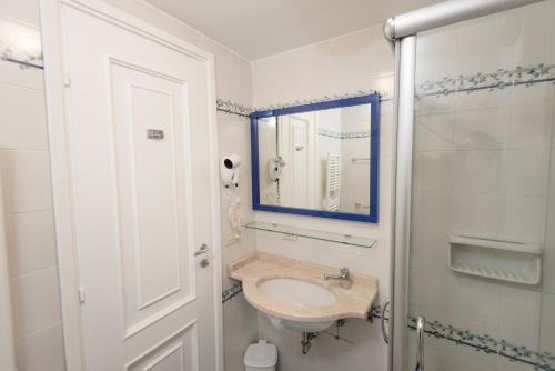 bagno bianco con lavandino e specchio di Mami Sabaudia Hotel a Sabaudia