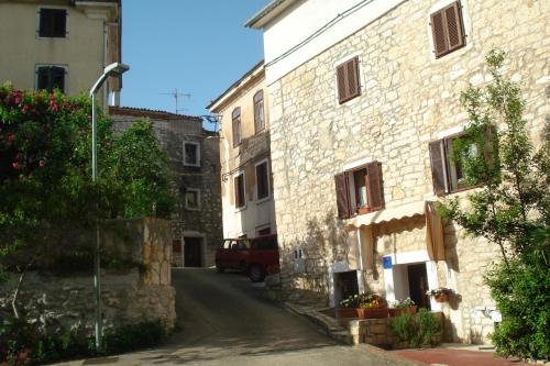 an alley in an old stone building with a red van at Maja Apartment in Višnjan