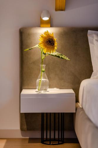 a vase with a sunflower on a table next to a bed at Rea Boutique Hotel in Himare