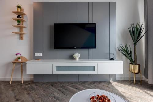 a living room with a tv on a white cabinet at Seaview Holiday Home, by Sanguine in Tanjong Tokong