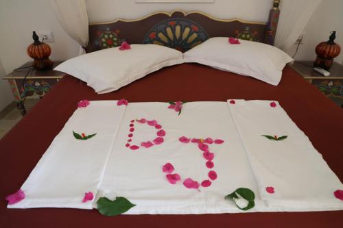 a bed with pink flowers on the sheets at Dar El Jerbi in Mezraya