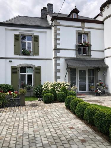 a white house with green shutters and a courtyard at La conciergerie in Hotton