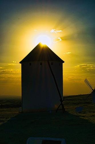 a building with the sun setting in the background at Hostal Restaurante Ego's in Campo de Criptana