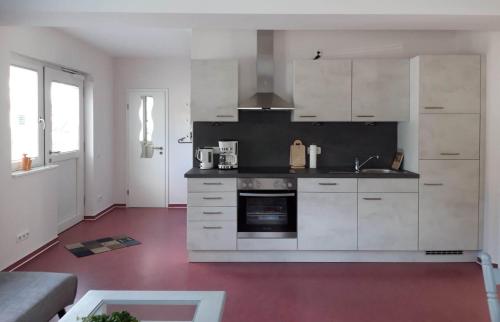 uma cozinha com armários brancos e um piso vermelho em Ferienwohnung Bad Laasphe em Bad Laasphe