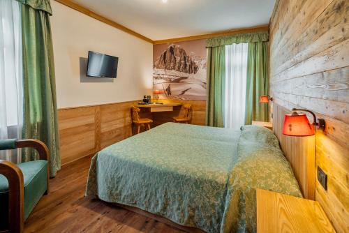 a hotel room with a bed and a desk at Hotel Corona in Cortina dʼAmpezzo
