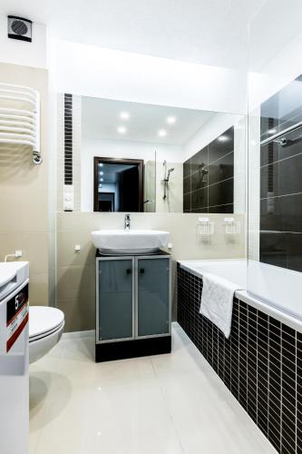 a bathroom with a sink and a tub and a toilet at Apartament MAJA 13 in Zakopane