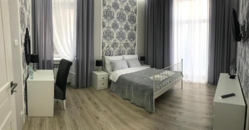a bedroom with a bed and a desk and windows at Apartament Mickiewicza - PKP Station in Przemyśl
