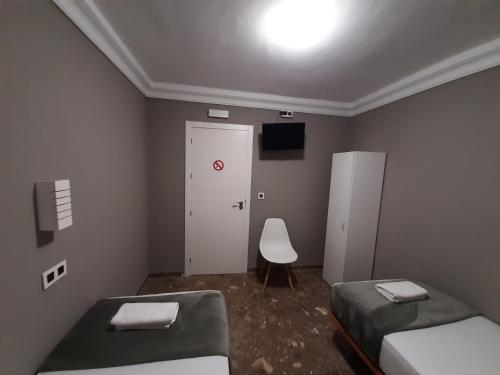 AYAMONTE ROOMS 43 في ايامونتي: غرفة صغيرة بسريرين وباب أبيض