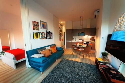 ein Wohnzimmer mit einem blauen Sofa und einer Küche in der Unterkunft Art District - POP & ROCK Apartments in Porto