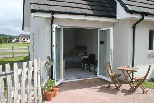 a patio with a bed and a table and chairs at The Snug at the Ski Lodge, Aviemore in Aviemore