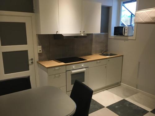 uma cozinha com armários brancos, uma mesa e um lavatório em Studio1 em Tromsø