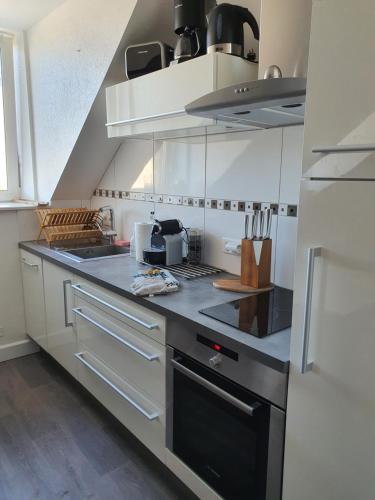 a kitchen with white cabinets and a stove top oven at Bord de Mer l'Appartement à Loctudy in Loctudy