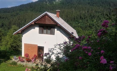 una pequeña casa blanca con sillas rojas y árboles en Planinska kuća ,,Furtula" Jahorina, en Pale