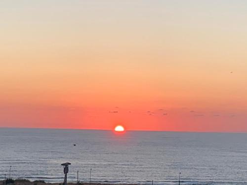 un tramonto sull'oceano con un ombrello di casa Cuffa a San Vito lo Capo