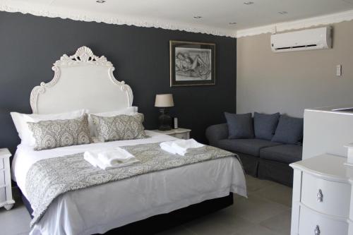 a bedroom with a large white bed with a couch at Le Grant Guesthhouse in Kroonstad