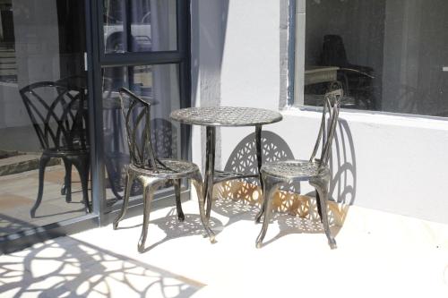 three chairs and a table on a porch at Le Grant Guesthhouse in Kroonstad