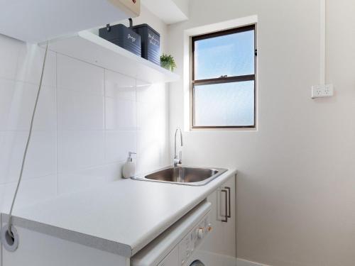 uma cozinha branca com uma pia e uma janela em Intrepid 1 3 Intrepid Close Amazing views of Shoal Bay only 100m from the Beach em Shoal Bay