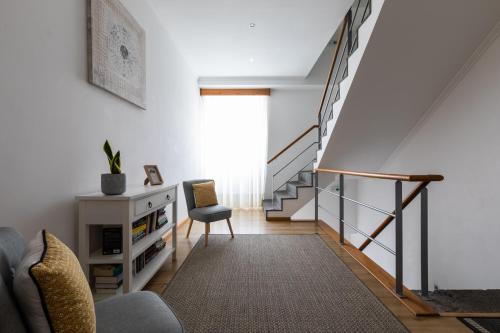 a living room with a staircase and a chair at Hotel Arcanjo in Rosário-Lagoa