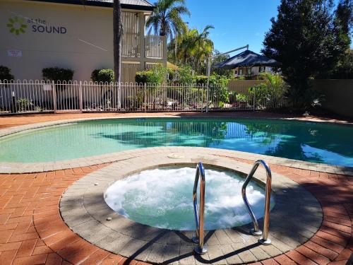 uma piscina com banheira de hidromassagem em frente a uma casa em At The Sound Noosa Motel em Noosaville