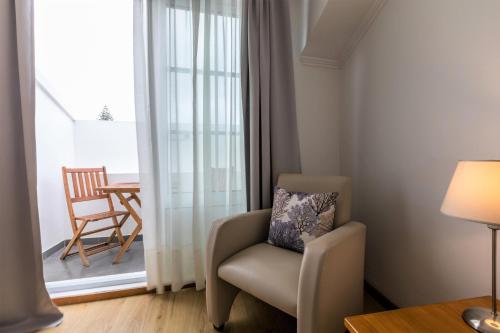 a living room with a chair and a window at Hotel Arcanjo in Rosário-Lagoa