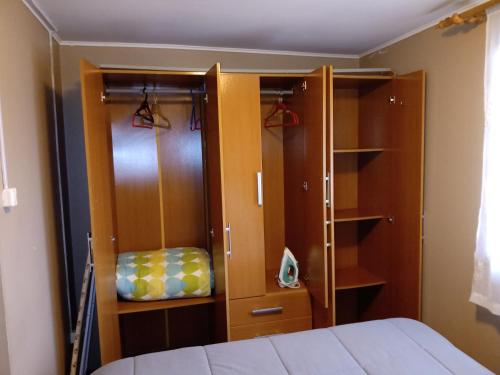 a bedroom with a bed and some wooden cabinets at CABAÑA EN PUERTO VARAS in Puerto Varas