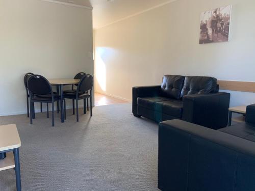 a living room with a couch and a table and chairs at Captain Cook Motor Lodge in Gisborne