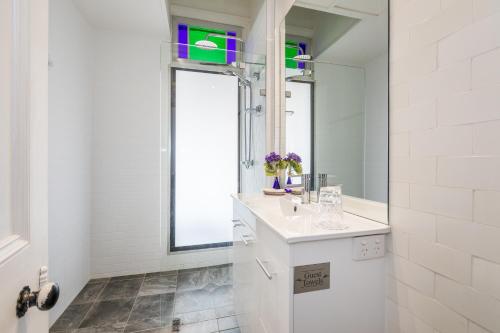 a white bathroom with a sink and a mirror at Cumquat House in Ipswich