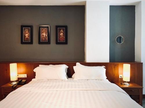 a bedroom with a large bed with three pictures on the wall at Point Boutique Hotel in Phnom Penh