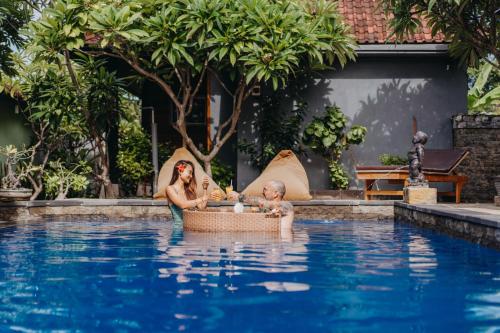 Eine Frau und ein Baby in einem Korb im Pool in der Unterkunft D and B Bungalow's by DeWizZ Management in Nusa Lembongan