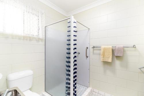 uma casa de banho com um chuveiro e um WC. em Yungaburra Park Motel em Yungaburra