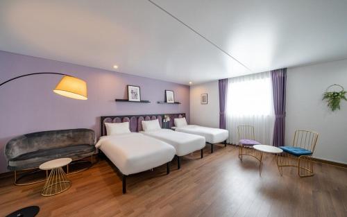 a hotel room with four beds and a couch at Hotel Hyggelig in Busan