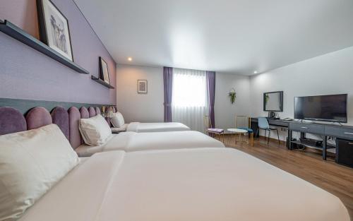a hotel room with three beds and a flat screen tv at Hotel Hyggelig in Busan