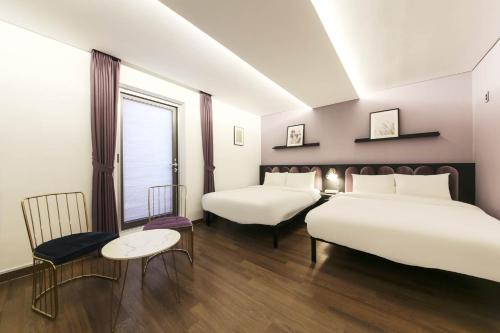 a bedroom with two beds and a table and chairs at Hotel Hyggelig in Busan
