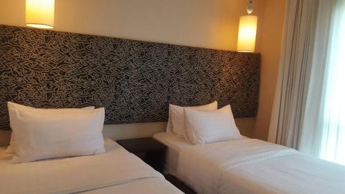 two beds in a hotel room with two pillows at At 21 Saladaeng in Bangkok